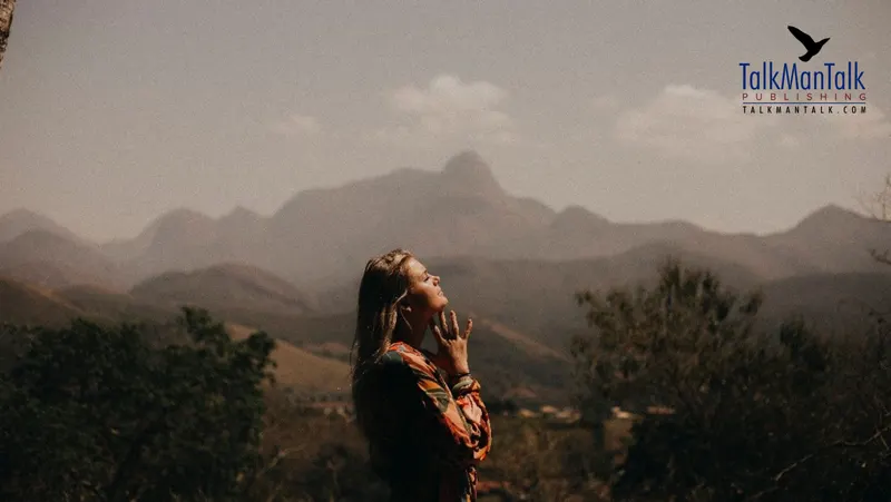 A woman looking up at the sky with mountains behind her