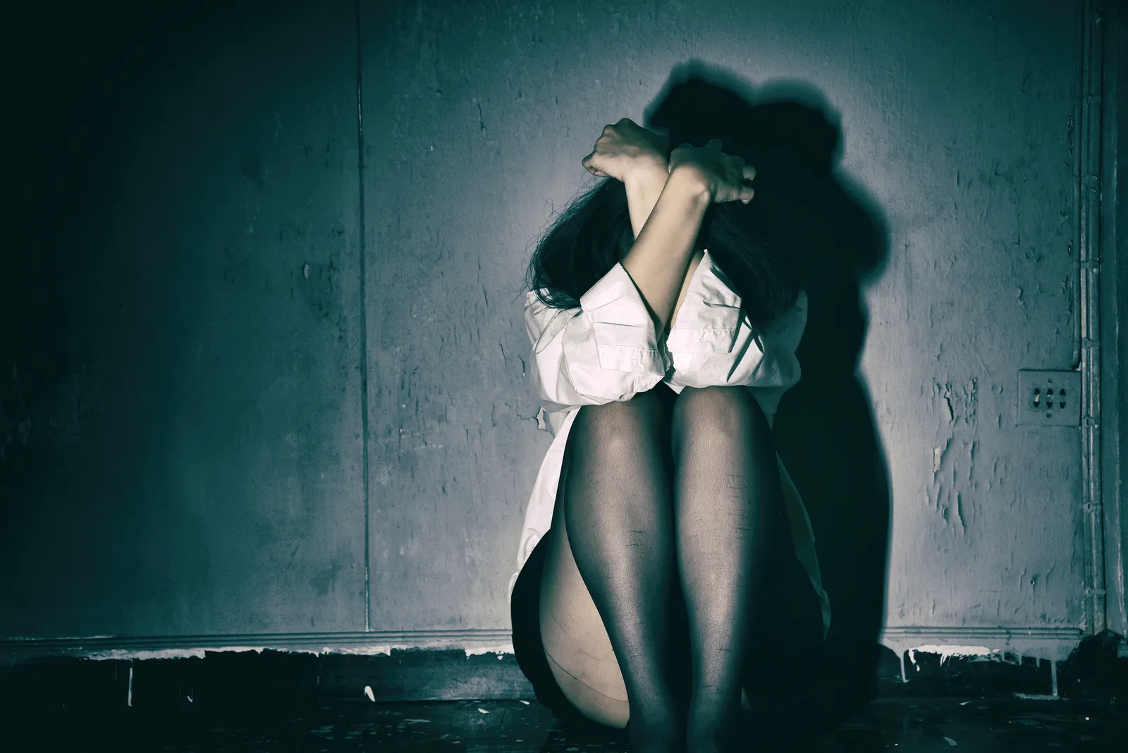 A woman sitting on the floor with her head buried in her arms