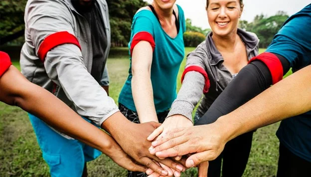 A group of people joining hands together outdoors